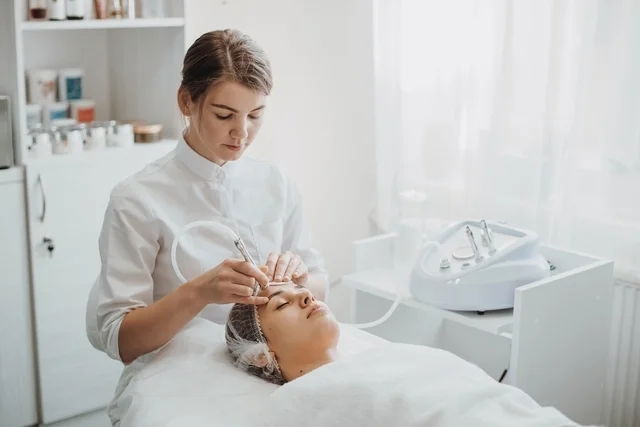 Esteticista realizando el tratamiento de punta de diamentes en la frente de una mujer