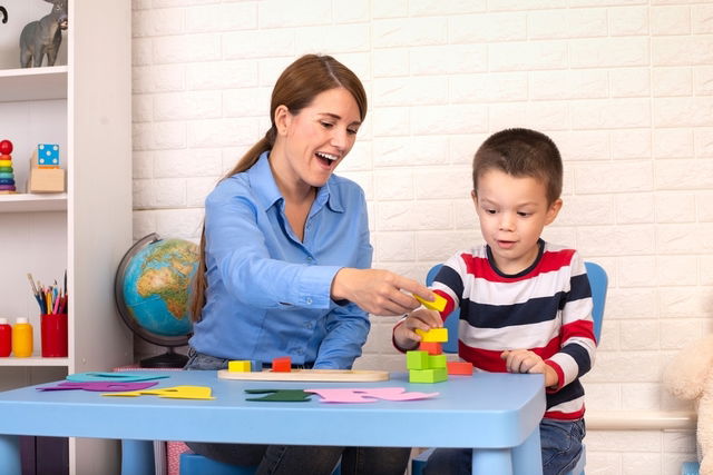 Niño realizando juegos en una mesa con uns terapeuta ocupacional