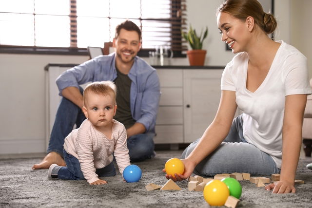 Bebê brincando com os pais no chão.