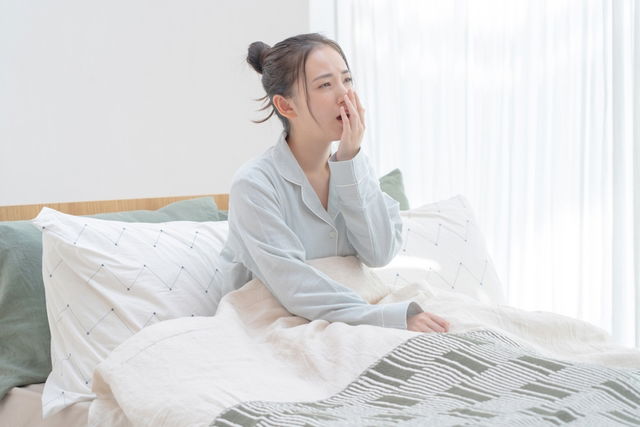 Mujer bostezando, sentada en la cama 