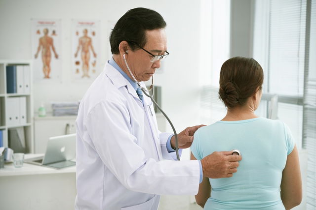 médecin en train d'ausculter une femme à l'aide d'un stéthoscope