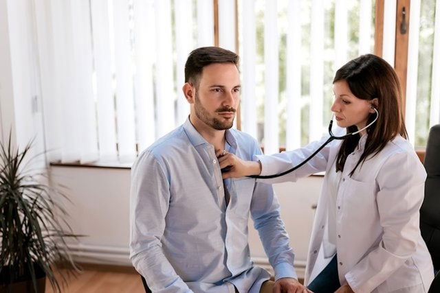 Cardiólogo escuchando el corazón del paciente con estetoscopio