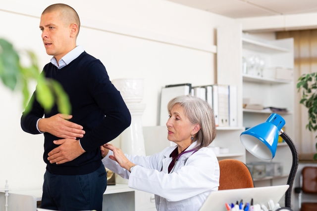 Nefrologista examinando um paciente jovem com desconforto no lado do abdome