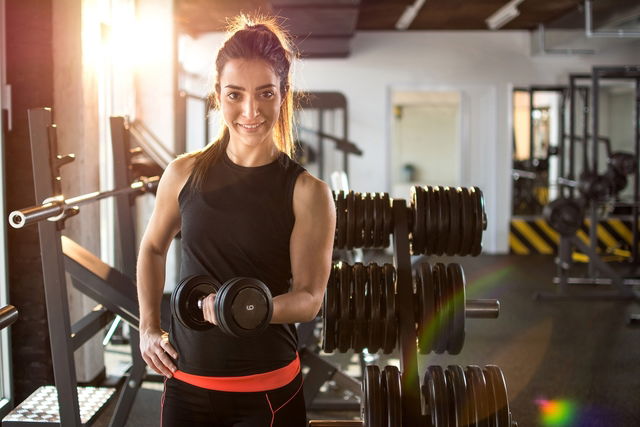 femme dans une salle de sport en train de pratiquer la musculation