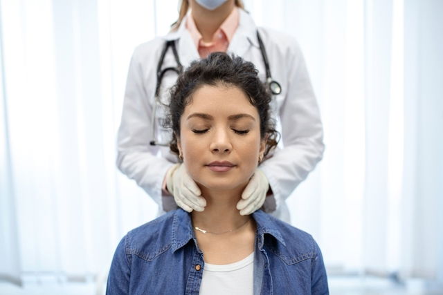 Endocrinóloga examinando el cuello de una mujer