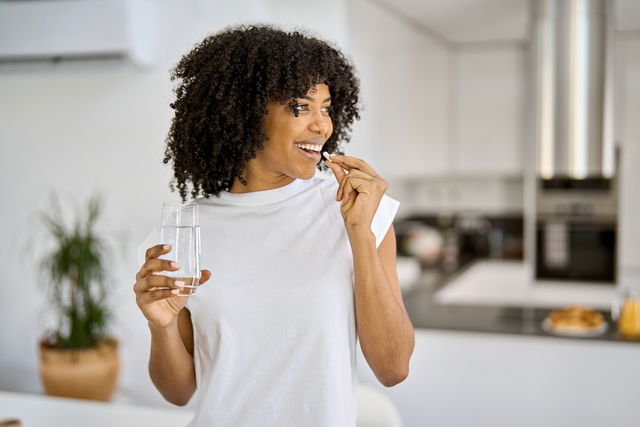 Mulher tomando comprimido com água