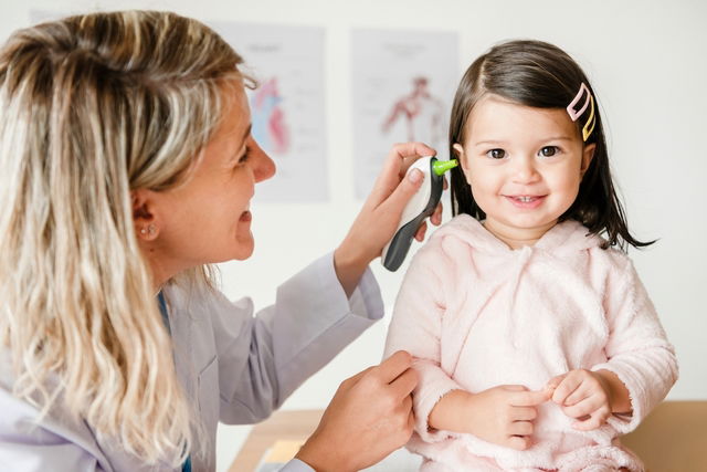 Pediatra midiendo la temperatura de un niño con un termómetro infrarrojo en el oído