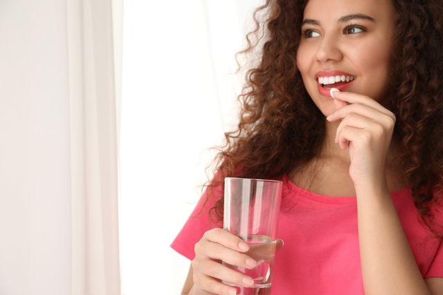 Mujer tomando un comprimido de dimenhidrinato