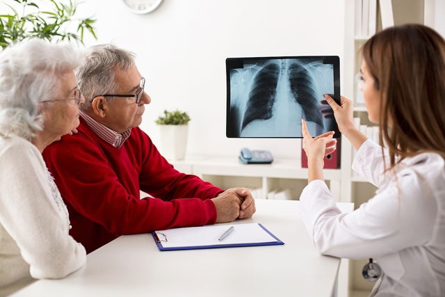 Médica em uma consulta mostrando uma radiografia de tórax a um paciente