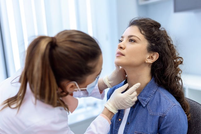 Médica examinando o pescoço de uma paciente.