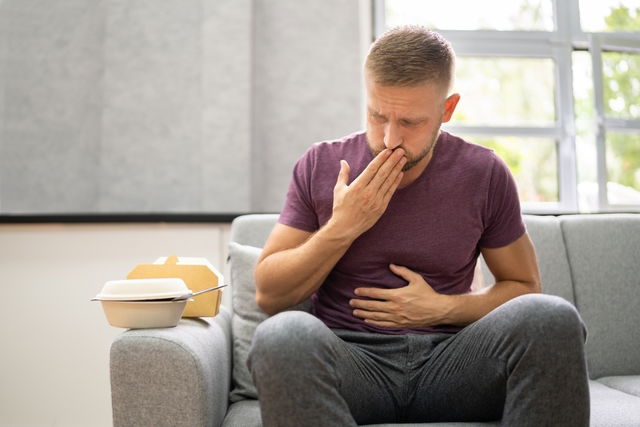 homme qui vient de manger et qui se touche le ventre et la bouche comme s'il voulait roter