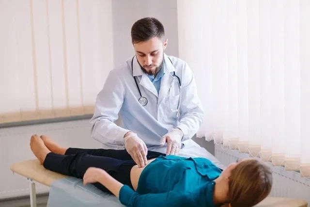 Médico haciendo un examen físico en el abdomen de una mujer