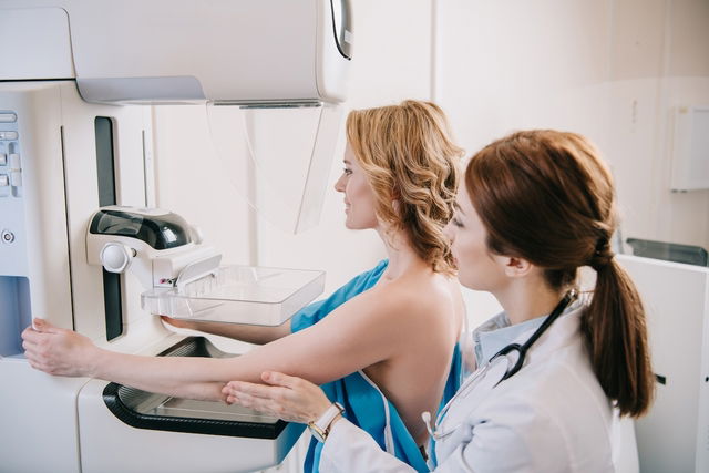 Mujer parada frente a la máquina de mamografía