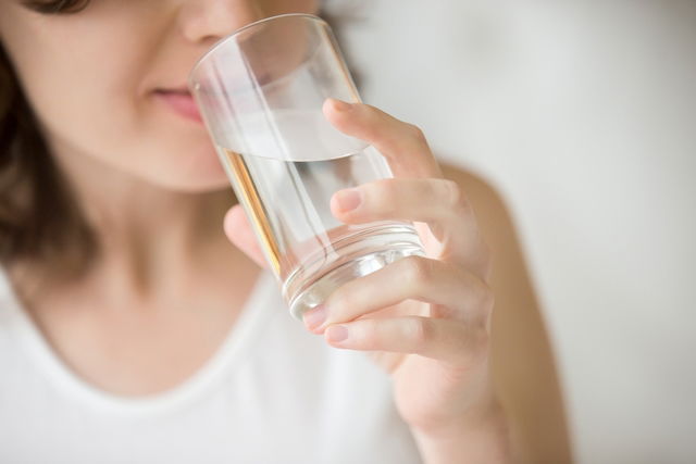 femme se plaignant de bouche sèche qui boit de l'eau