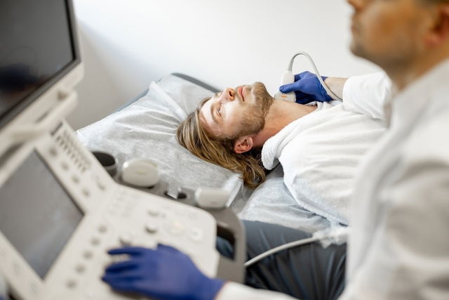 Médico realizando un Doppler carotídeo a un joven