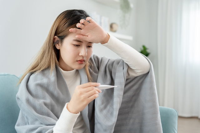 Mujer con termómetro verificando su temperatura