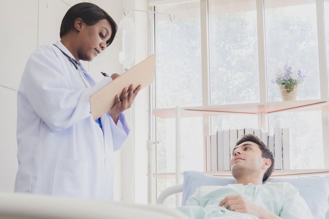 Médica conversando com um paciente jovem acamado