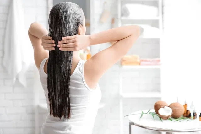 Mujer lavándose el cabello para eliminar la caspa