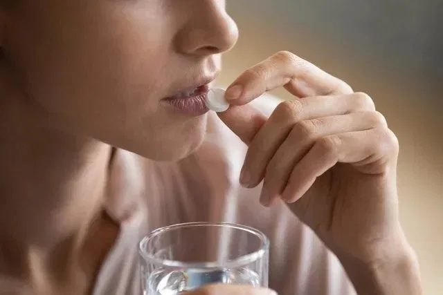 Mujer tomando una pastilla de ácido fólico