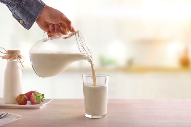 Persona sirviendo un vaso de leche