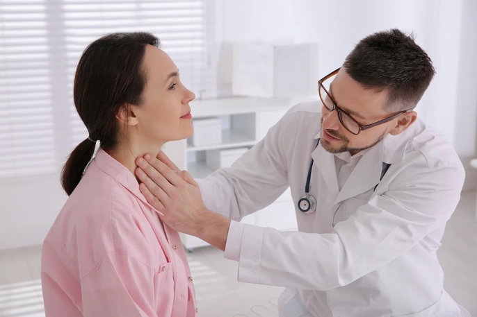 doctor checking woman's thyroid