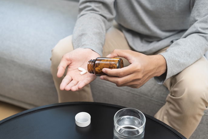 Man pouring supplements into palm