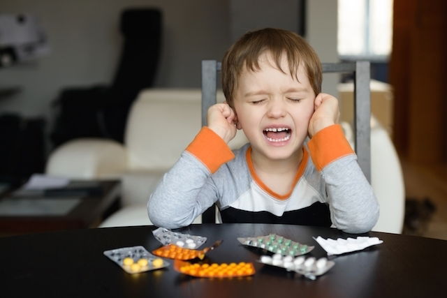 enfant agité et criant qui se bouche les oreilles avec les mains