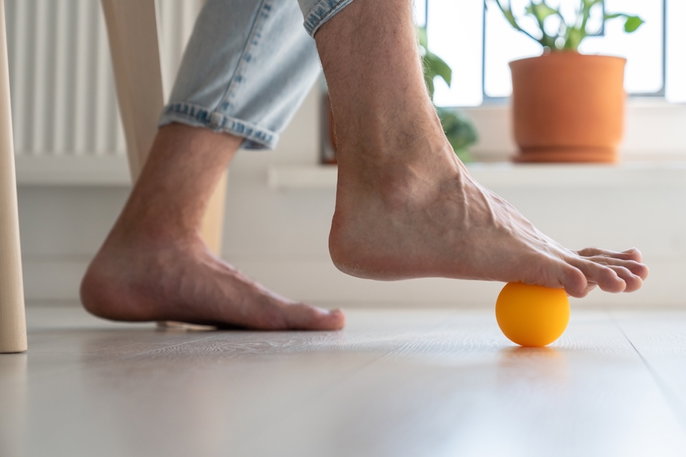 Hombre realizandose un masaje con pelota para juanetes