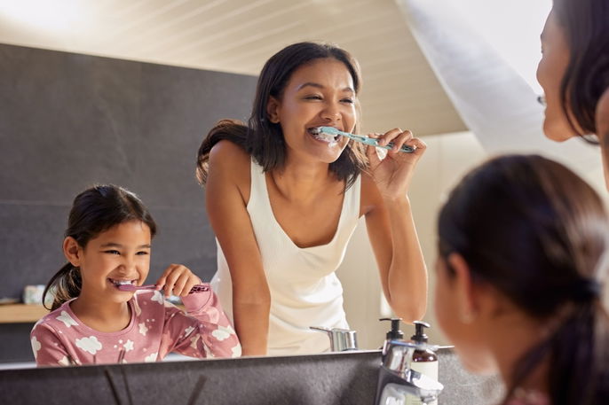 Mujer y niña lavandose los dientes