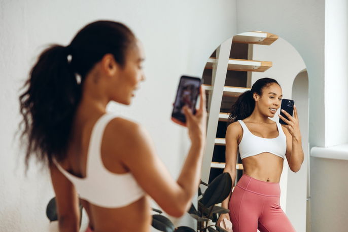 Young woman checking stomach in mirror