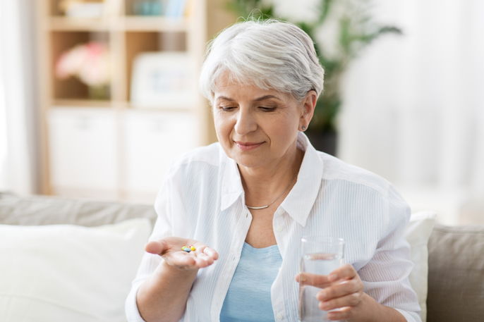 Elderly woman holding a dapagliflozin tablet in her hand 