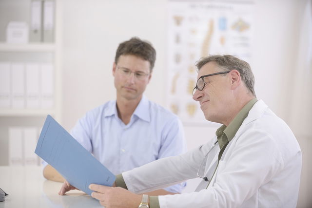 Doctor mirando los resultados de los exámenes presentados por el paciente en la consulta