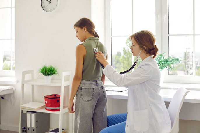 Médico pneumologista auscultando a respiração de uma jovem