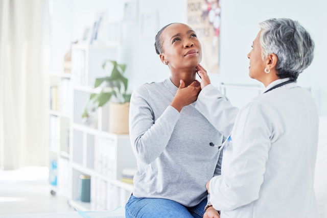 médecin en train de palper la gorge d'une femme