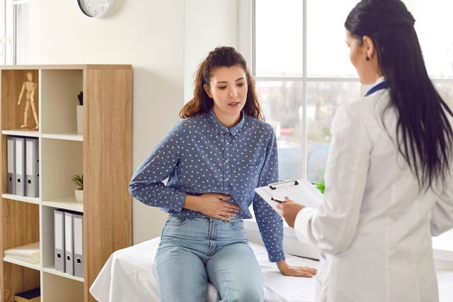 femme en consultation médicale se touchant le ventre de façon douloureuse