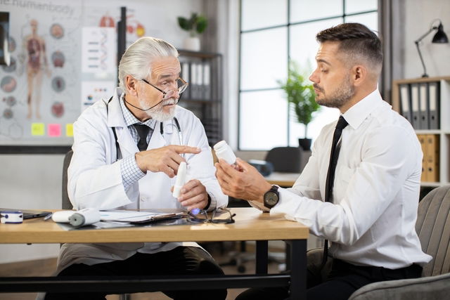 Médico explicando o efeito do medicamento para o paciente no consultório