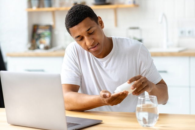 Homem retirando comprimidos de um pote