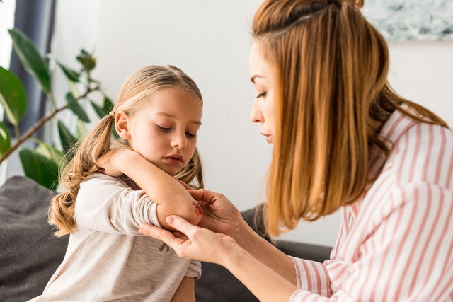 Mère s'occupant d'une blessure au coude de l'enfant