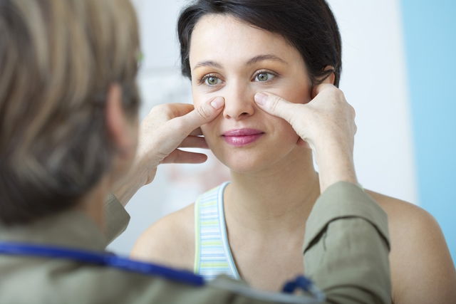 médecin en train de palper les sinus d'une femme