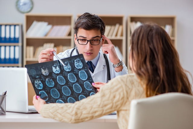 Médico explicando o exame de ressonância magnética do crânio para a uma paciente