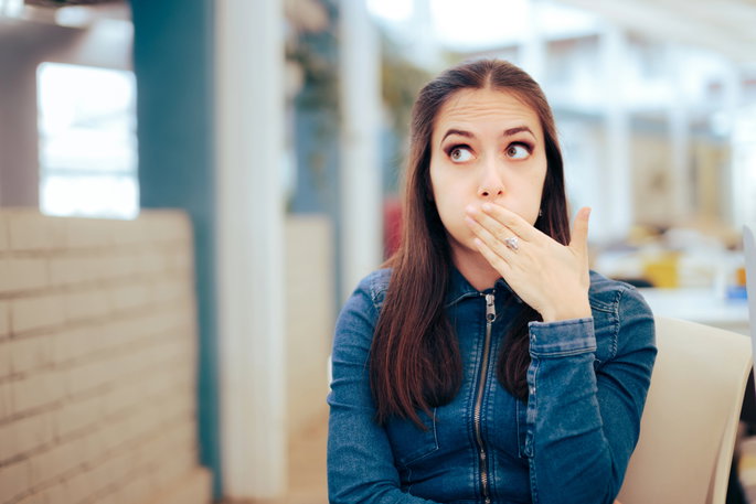 woman at a restaurant covering her mouth while burping