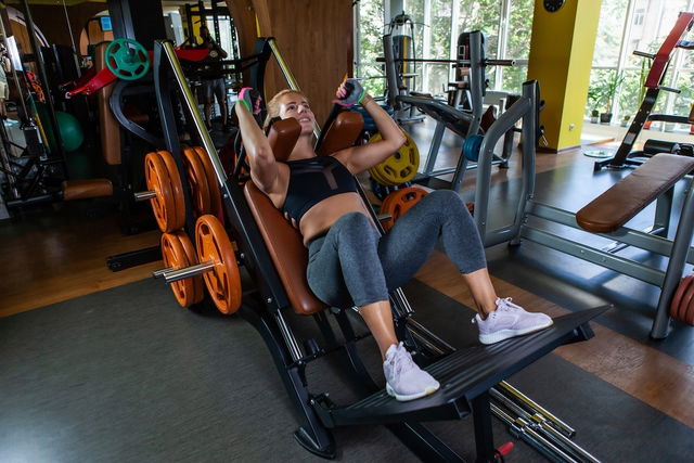 femme en train de réaliser un hack squat à la salle de sport