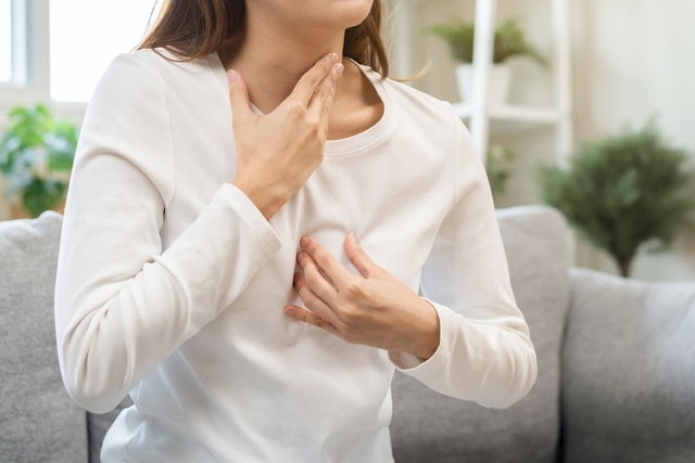 Mujer agarrándose la garganta y el pecho 