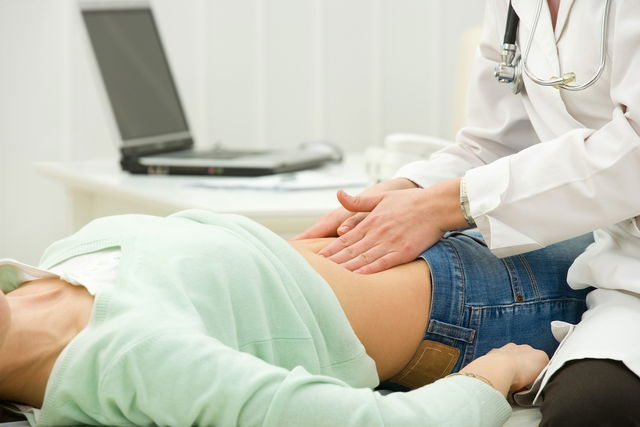 Médico palpando el abdomen de una paciente