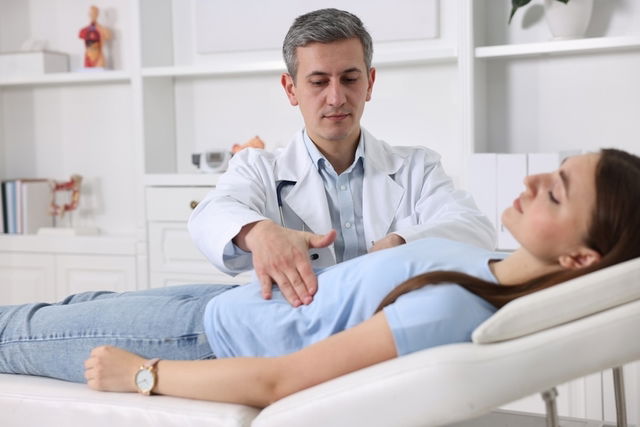 Gastroenterólogo examinando a una mujer joven en el abdomen