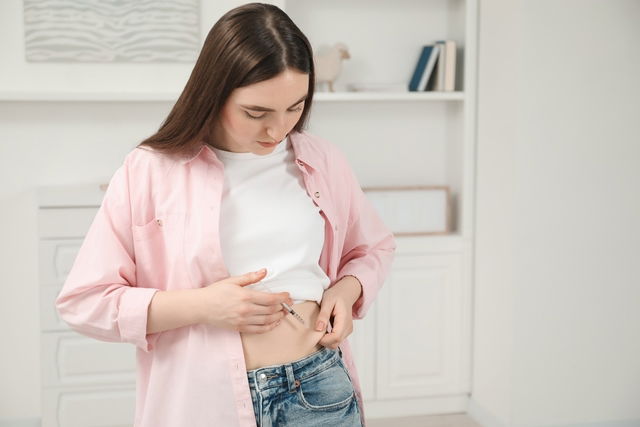 Mulher aplicando insulina sob a pele da barriga