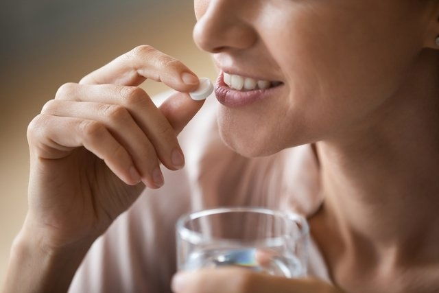 Woman holding pill to her mouth