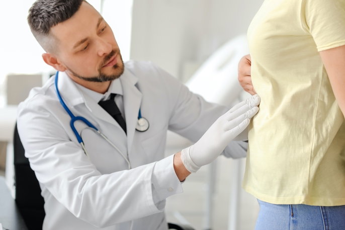 Doctor assessing woman's abdomen