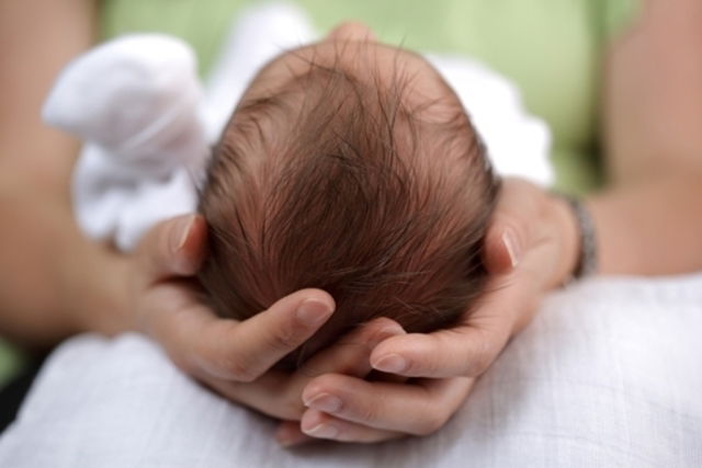 Madre sosteniendo la cabeza de su bebé recién nacido