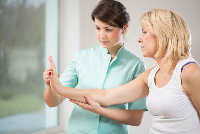 Health care porfessional assessing woman's wrist range of motion